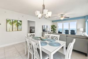 a dining room and living room with a white table and chairs at A Wave From it All Oceanfront Pool Condo in Daytona Beach
