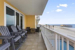 a balcony with chairs and a view of the beach at A Wave From it All Oceanfront Pool Condo in Daytona Beach