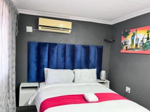 a bedroom with a large bed with a blue headboard at Executive Galaxy Guest House Nkowankowa Extension 2 in Tzaneen