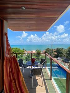 a balcony with a table and chairs and the ocean at Casa de condomínio na praia de cototelo com bela vista para o mar in Parnamirim