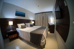a hotel room with a large bed and a desk at Hellix Flat Itaboraí in Itaboraí