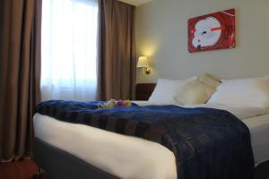 a hotel room with a bed with a blue blanket on it at Maritim Hotel in Tønsberg