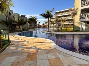 a swimming pool in a resort with palm trees and buildings at Encanto Moanara in Luis Correia