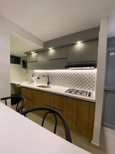 a kitchen with a sink and a counter with chairs at Apartamento Vacacional in Armenia