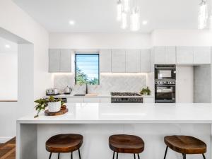 a kitchen with a white counter and two stools at Coastal Dream BeachFront Oasis in Newcastle +44 photos