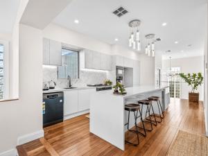 a kitchen with white cabinets and a island with bar stools at Coastal Dream BeachFront Oasis in Newcastle