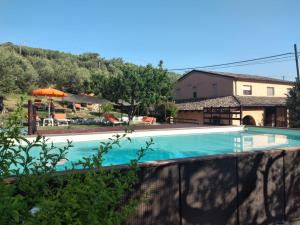 a swimming pool with a house and an umbrella at Villa Elster Country House in Collecorvino