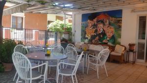 eine Terrasse mit Tischen und Stühlen und ein Wandbild in der Unterkunft Hotel Eleonora in Rimini
