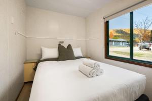 a bedroom with a large white bed with a window at Bright Riverside Holiday Park in Bright