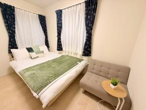 a bedroom with a bed and a chair and a table at 池袋鑫の屋 in Tokyo