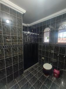 a bathroom with a black tiled shower with a toilet at Residence Efrata Casa Inteira in Itaboraí +27 photos