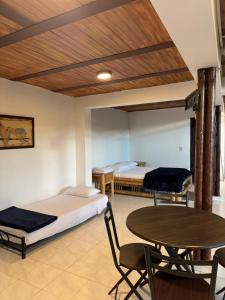 a room with two beds and a table and a bed at Cabaña Las Ceibas in Nocaima