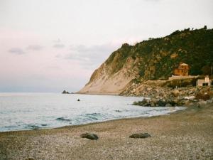 a rocky beach with a house on the side of a mountain at Holiday Home in Carlentini with Swimming Pool,Garden,Terrace in Agnone Bagni