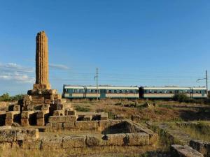 a train is traveling through a field with a column at Holiday Home in Carlentini with Swimming Pool,Garden,Terrace in Agnone Bagni