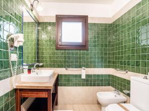 a green tiled bathroom with a sink and a toilet at Holiday Home in Carlentini with Swimming Pool,Garden,Terrace in Agnone Bagni
