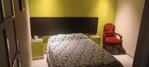 a bedroom with a bed and a red chair at Posada Casa Blanca in Cedro