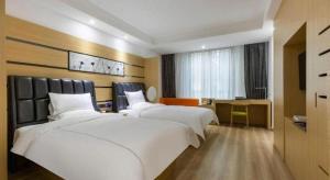 ein Hotelzimmer mit zwei Betten und einem Schreibtisch in der Unterkunft Wuxi Zenmore Hotel in Wuxi + 152 Fotos