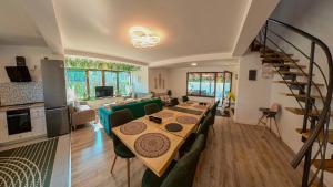 a living room with a long table and a kitchen at Jungle Family Villa near Park Aventura,Lake,Zoo in Braşov +15 photos