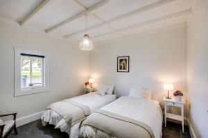 two beds in a room with white walls at Bungalow on Chambers in Napier
