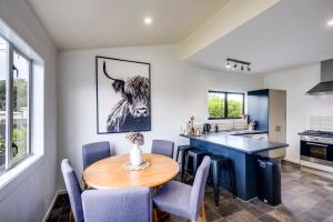 a kitchen with a wooden table and blue chairs at Bungalow on Chambers in Napier +7 photos