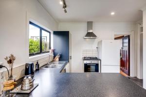 a kitchen with a black counter top and a refrigerator at Bungalow on Chambers in Napier