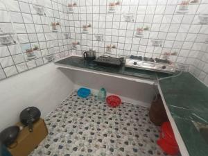 cocina pequeña con fogones y suelo de baldosa. en Aman Homestay, en Saur