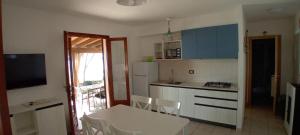 a kitchen with a table and chairs and a kitchen with blue cabinets at INCANTEVOLE VILLINO SUL MARE con accesso diretto alla spiaggia, posto auto e aria condizionata! in Capoliveri