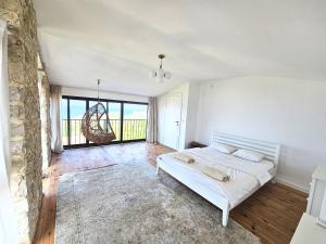 a white bedroom with a bed and a large window at Stone Villa at the Vrelo in Dobra Voda +12 photos