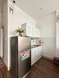 a kitchen with a black refrigerator and white cabinets at Chỗ nghỉ cuối tuần in Hanoi
