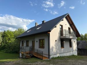 uma pequena casa branca com um telhado preto em Domki Pod Wzgórzem em Polańczyk