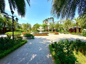 a park with a fountain and palm trees and a building at Delux Studio In Vinhomes Green Bay Near WJ Marriott Hotel in Hanoi