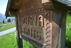 een houten bord waarop staat australire op een paal bij Ustria / Pensiun Trutg in Vella