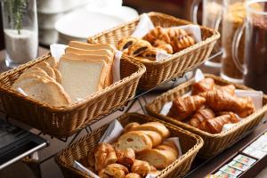 four baskets of bread and pastries on a table at ANA Holiday Inn Kanazawa Sky by IHG in Kanazawa