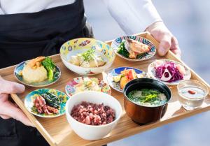 a person holding a tray with bowls of food at ANA Holiday Inn Kanazawa Sky by IHG in Kanazawa +37 photos