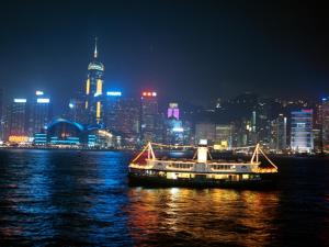 un bateau sur l'eau avec une ville la nuit dans l'établissement London Guest House, à Hong Kong