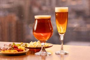 two glasses of beer and a plate of food on a table at ANA Holiday Inn Kanazawa Sky by IHG in Kanazawa