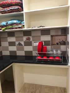 a kitchen counter with red dishes on a shelf at Chinmayi Guest Suite in Avanigadda +2 photos