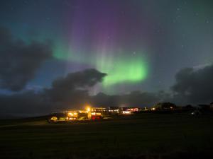 an aurora in the sky over a field at night at Stóra-Mörk Guesthouse in Stora Mork