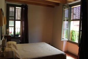 a bedroom with a bed and two windows at B&B Alla Santella in Calvagese della Riviera