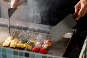 a person is cooking food on a grill at ANA Holiday Inn Kanazawa Sky by IHG in Kanazawa