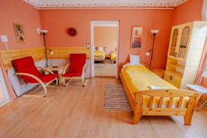 a bedroom with orange walls and a bed and two red chairs at Sárga ház a Kék úton - Becske in Becske