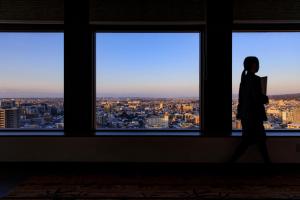 a woman walks through a window looking out at a city at ANA Holiday Inn Kanazawa Sky by IHG in Kanazawa