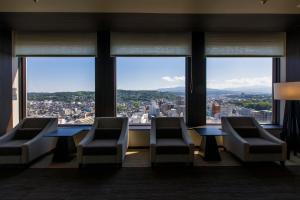a room with chairs and tables and large windows at ANA Holiday Inn Kanazawa Sky by IHG in Kanazawa