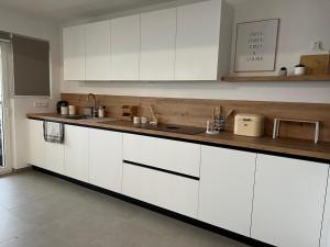 a kitchen with white cabinets and a wooden counter top at En Bord de Mer in Middelkerke +3 photos
