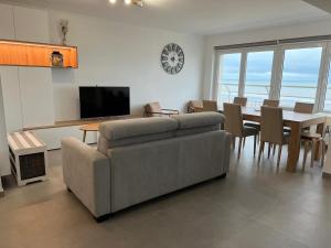 a living room with a couch and a table with chairs at En Bord de Mer in Middelkerke