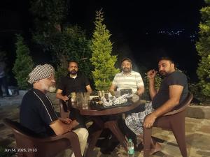 a group of men sitting around a table at night at Oak Retreat Huts in Shimla