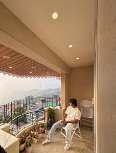 a man sitting in a chair on a balcony with a view at The Erina House in Darjeeling +25 photos