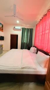 a bedroom with a large bed with red curtains at RAGANT Hotel in Cape Coast