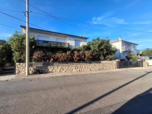 a house on the side of a street with a stone wall at Apartman Vitamare 160 m from the beach in Novi Vinodolski