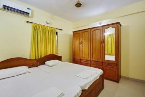 a bedroom with two beds and a wooden cabinet at Saikunj Holiday Homes in Candolim